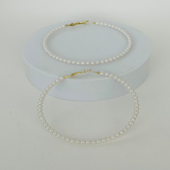 Close-up image of pearl hoop earrings featuring lustrous white pearls on a sleek gold hoop, ideal for elegant and modern styles.