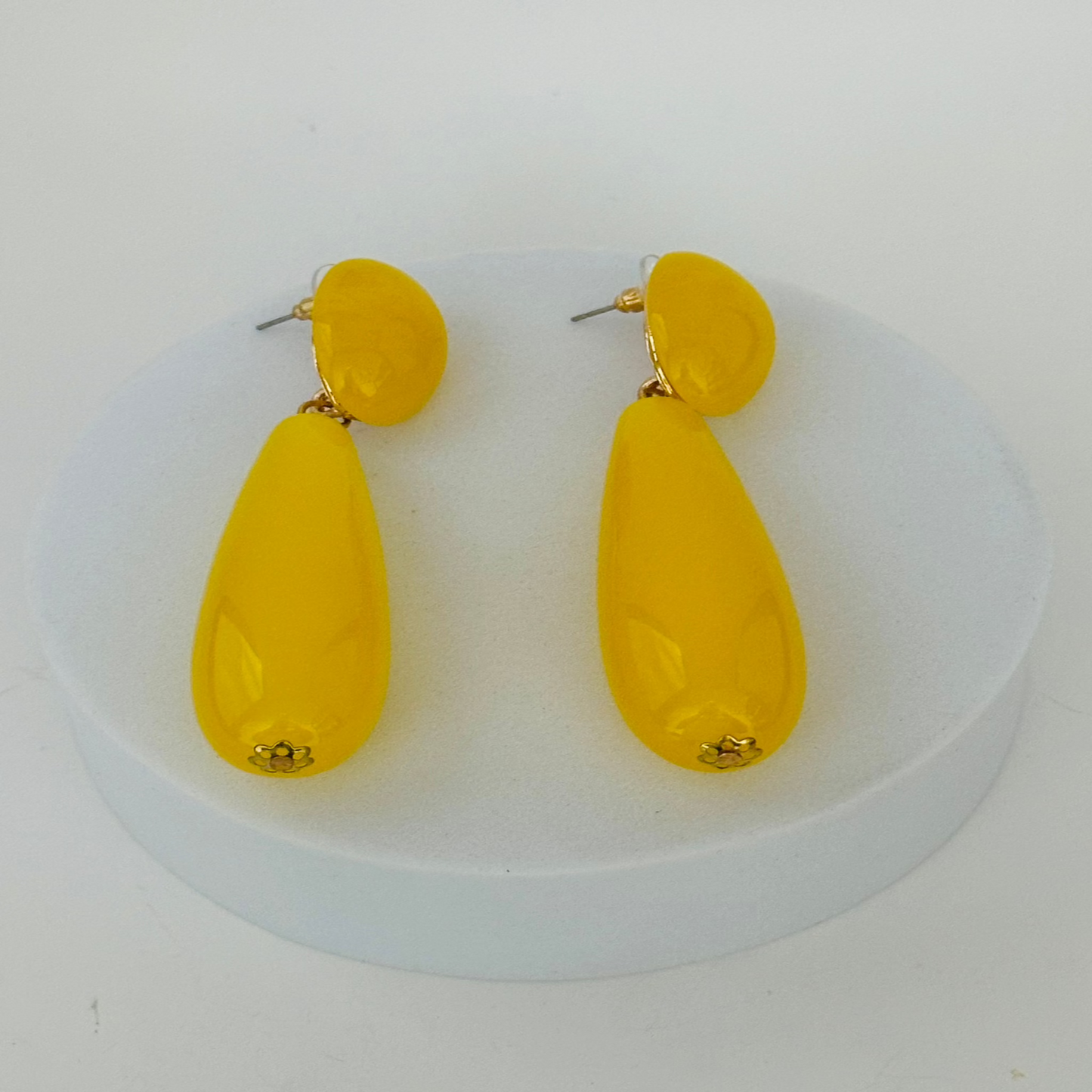 Close-up image of elegant yellow earrings with a sleek gold finish, perfect for adding a pop of color to any outfit.