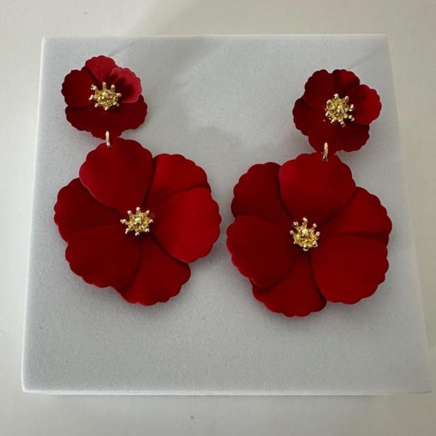 Close-up image of red floral earrings with intricate petal details, perfect for making a bold and elegant statement.