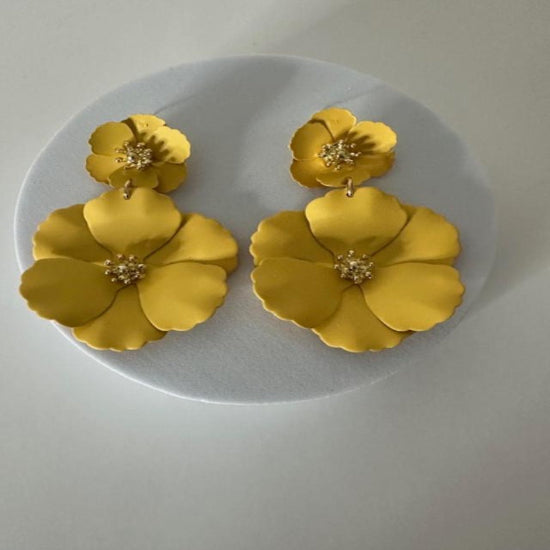 Pair of gold floral earrings on a white plate