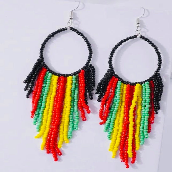 A pair of beaded tassel drop earrings with red, yellow, green, and black strands against a white background.