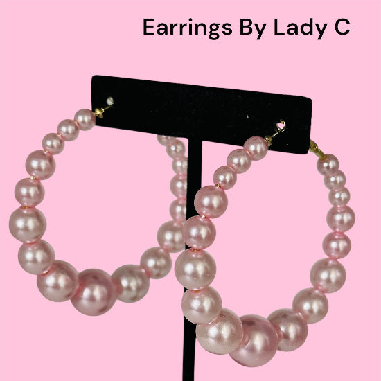 Pearl hoop earrings on a black stand with 'Earrings By Lady C' text on a pink background