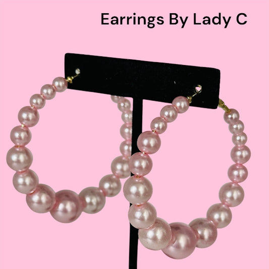 Pearl hoop earrings on a black stand with 'Earrings By Lady C' text on a pink background