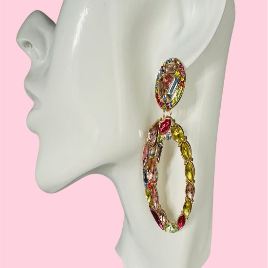 Multicolored hoop earrings on a mannequin ear with a pink background