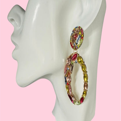 Multicolored hoop earrings on a mannequin ear with a pink background