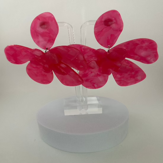 Large flower-shaped stud earrings in vibrant hot pink, featuring bold, detailed petals with a glossy finish. 