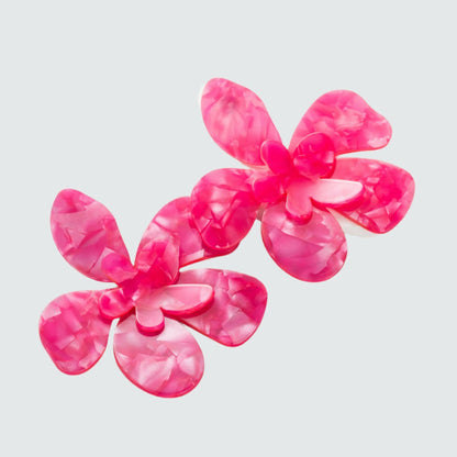 Large flower-shaped stud earrings in vibrant hot pink, featuring bold, detailed petals with a glossy finish.